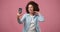 Smiling happy arican american woman in jeans shirt making selfie on smartphone over pink studio background