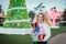 Smiling happy blonde curly woman with tower of colorful gift boxes in hands, enjoying time outdoors in decorated park with