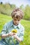 Smiling happy boy sitting in grass outside picking flowers