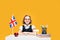 Smiling happy caucasian schoolgirl sitting at the desk during English lesson. Great Britain flag