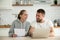 Smiling happy couple talking at home kitchen with laptop papers