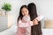Smiling happy cute korean teen girl in pajama hugging young lady in bedroom interior