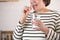 Smiling happy healthy senior woman at home holding glass of natural water taking daily pill for good health and senile