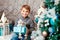 Smiling happy little boy sitting with christmas present near the chrismas tree