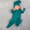 Smiling happy newborn infant one month baby in the green clothes on bed bright airy copy space childhood