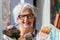 Smiling happy older woman portrait, proud artist, in her fifties with grey hair and black glasses and many paintbrushes