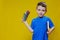 Smiling happy schooler in blue t-shirt holding multicolored pencils and book on yellow background