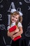 Smiling happy schoolgirl standing coquettishly before the chalkboard as a background with a couple of books hugging them