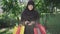 Smiling happy woman in hijab standing in sunrays with shopping bags and pack of dollars. Portrait of joyful young Middle