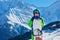 Smiling happy young boy stand with snowboard over the mountains