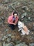 Smiling happy young girl with enameled mug with tea in hands and smart beautiful dog Japanese akita inu on a stony shore.