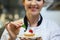 Smiling head chef putting mint leaf on little cake on plate