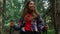 Smiling hiker walking in green forest. Attractive girl trekking in green woods