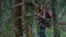 Smiling hiker walking between trees in forest. Positive girl hiking in woods