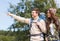 Smiling hikers with backpacks pointing finger