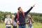 Smiling hikers with backpacks pointing finger