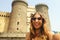 Smiling hipster woman with sunglasses taking selfie photo in Naples with Castel Nuovo castle on the background, Naples, Italy