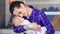 Smiling hipster young mother hugging her sleeping little baby holding by hand medium close-up