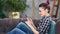 Smiling hipster young woman chatting using smartphone sitting on couch at home medium shot
