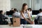 Smiling hired female company employee unpacking box with persona