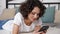 Smiling hispanic curly woman student uses smartphone tapping screen display