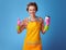 Smiling housewife with coffee cup showing thumbs up on blue