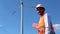 Smiling indian engineer next to a wind farm and power pole