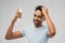 Smiling indian man applying hair spray over gray