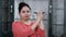 Smiling Indian woman applauding while standing against a blurred background