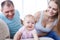 Smiling infant crawling on sofa and good-looking parents looking