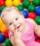 Smiling infant playing among colorful balls