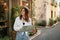 Smiling inspired millennial european lady tourist in hat with map looks at sights searching for route travel in city