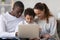 Smiling international family with kid using laptop at home