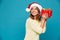 Smiling intrigued woman in sweater and christmas hat holding gift