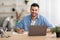 Smiling israeli man working on laptop at home