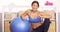 Smiling Japanese woman resting on workout ball