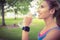 Smiling jogger woman drinking water in park