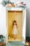 Smiling, jolly, cute barefoot preschool girl with Christmas gift box standing inside of open wardrobe at home