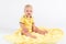 Smiling kid boy on the plush yellow blanket on the white background