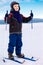 Smiling kid boy skier standing in snow