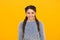 Smiling kid girl with stylish braided hair on yellow background, knitwear