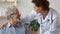 Smiling kind female general practitioner embracing shoulders of elderly patient.