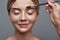 Smiling lady feeling pleased while having her eyebrows brushed