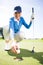 Smiling lady golfer kneeling on the putting green