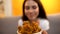 Smiling lady smelling appetizing roasted chicken legs at fast food restaurant