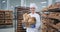 Smiling large charismatic mature baker woman holding a vintage basket with organic bread and looking straight to the