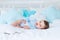 Smiling or laughing baby boy on the bed to sleep, healthy happy little baby in blue bodysuit