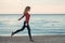 Smiling laughing excited Caucasian young woman in jeans running jumping among seagulls birds