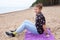 Smiling and laughing teen age girl sitting on sandy beach, northern seacoast