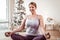 Smiling light-haired woman with curvy figure meditating on wooden floor